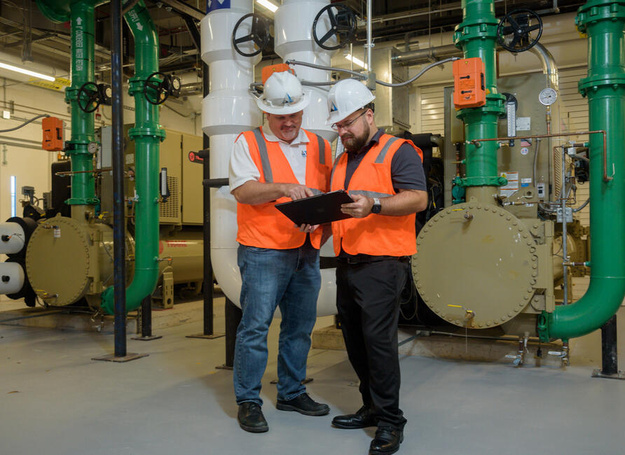 ACE Mechanical technicians reviewing commercial HVAC equipment in a mechanical room